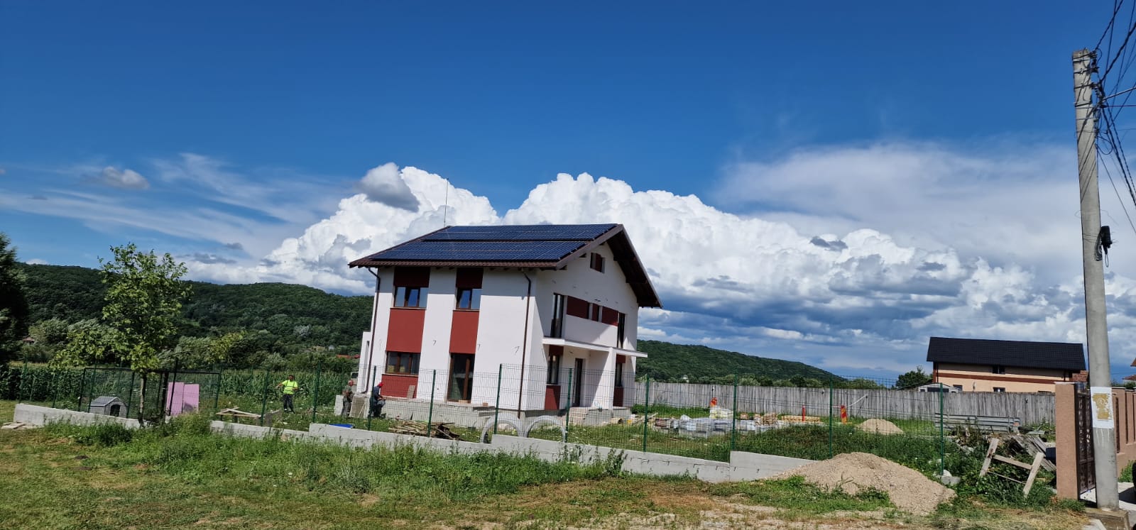 Casă rezidențială cu panouri fotovoltaice pe acoperiș, zonă de deal