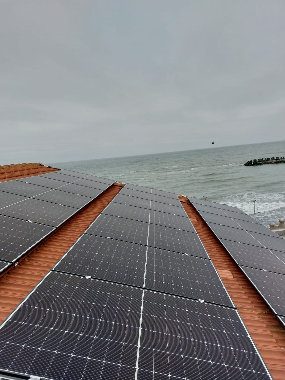 Panouri fotovoltaice pe acoperiș cu vedere la mare